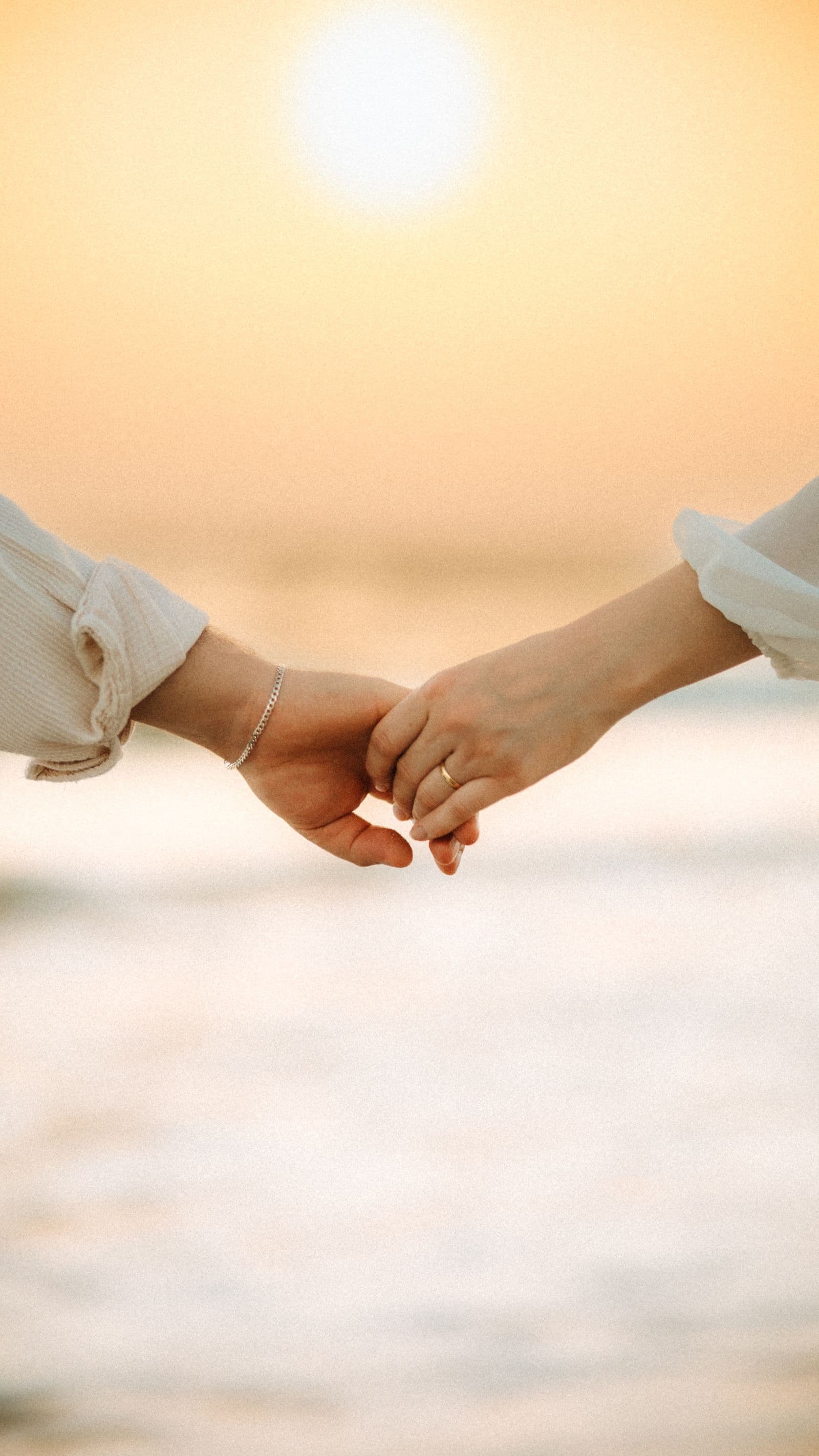 Mãos de um casal entrelaçadas ao entardecer