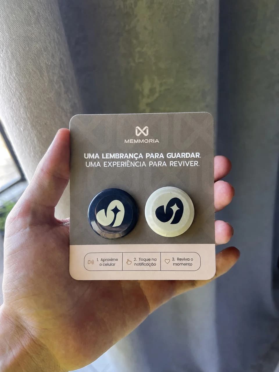 Foto real de dois bottons Memmoria apresentados no cartão da marca